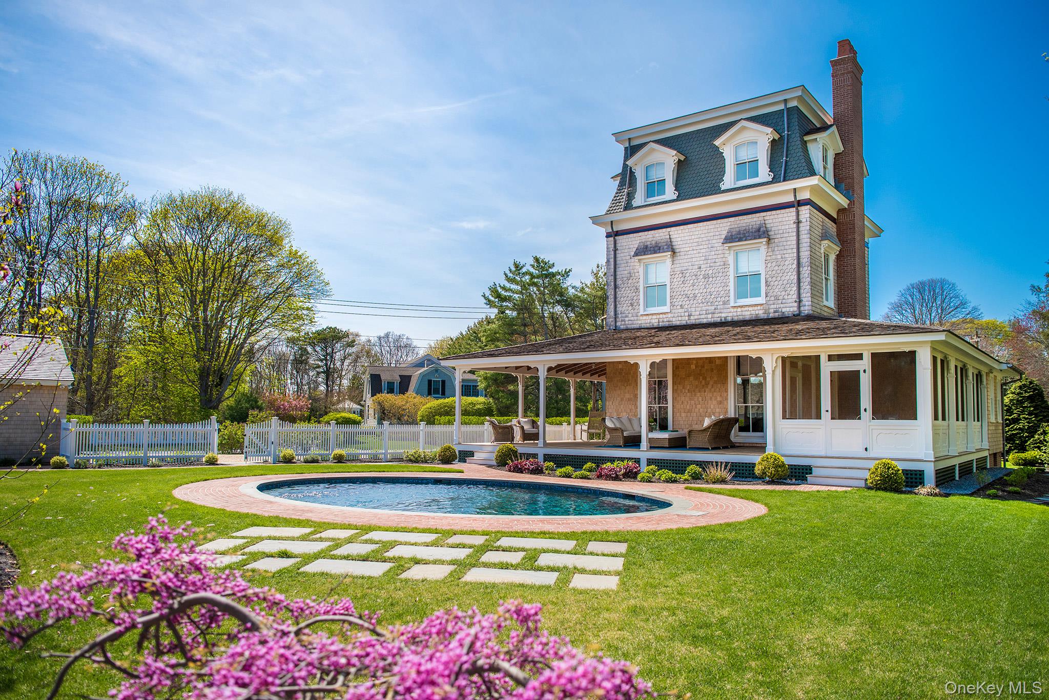 a front view of house and yard with swimming pool and trees in the background