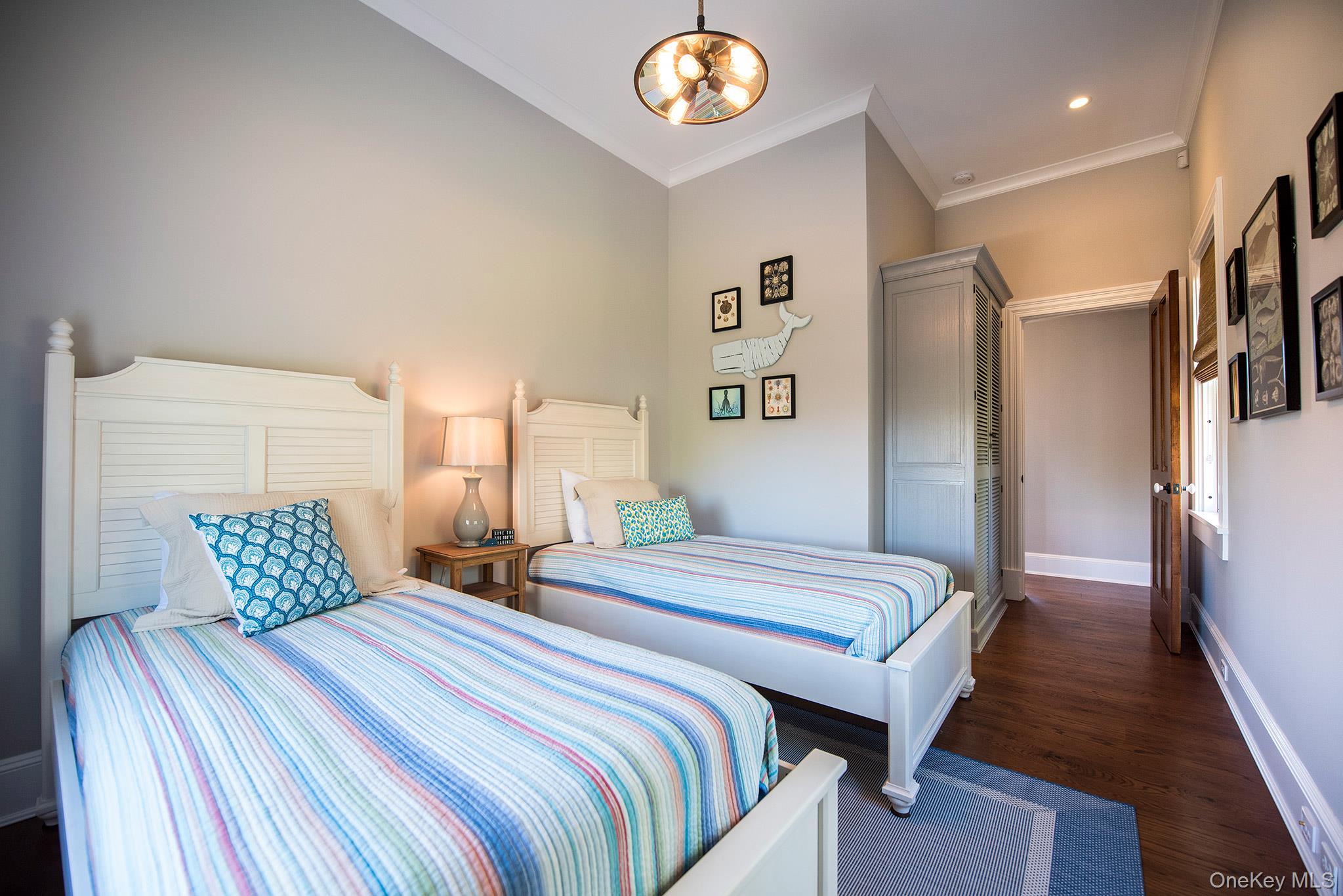 106 Old Depot Road Quogue, NY 11959 - Photo 21 of 34 a bedroom with two beds and a chandelier