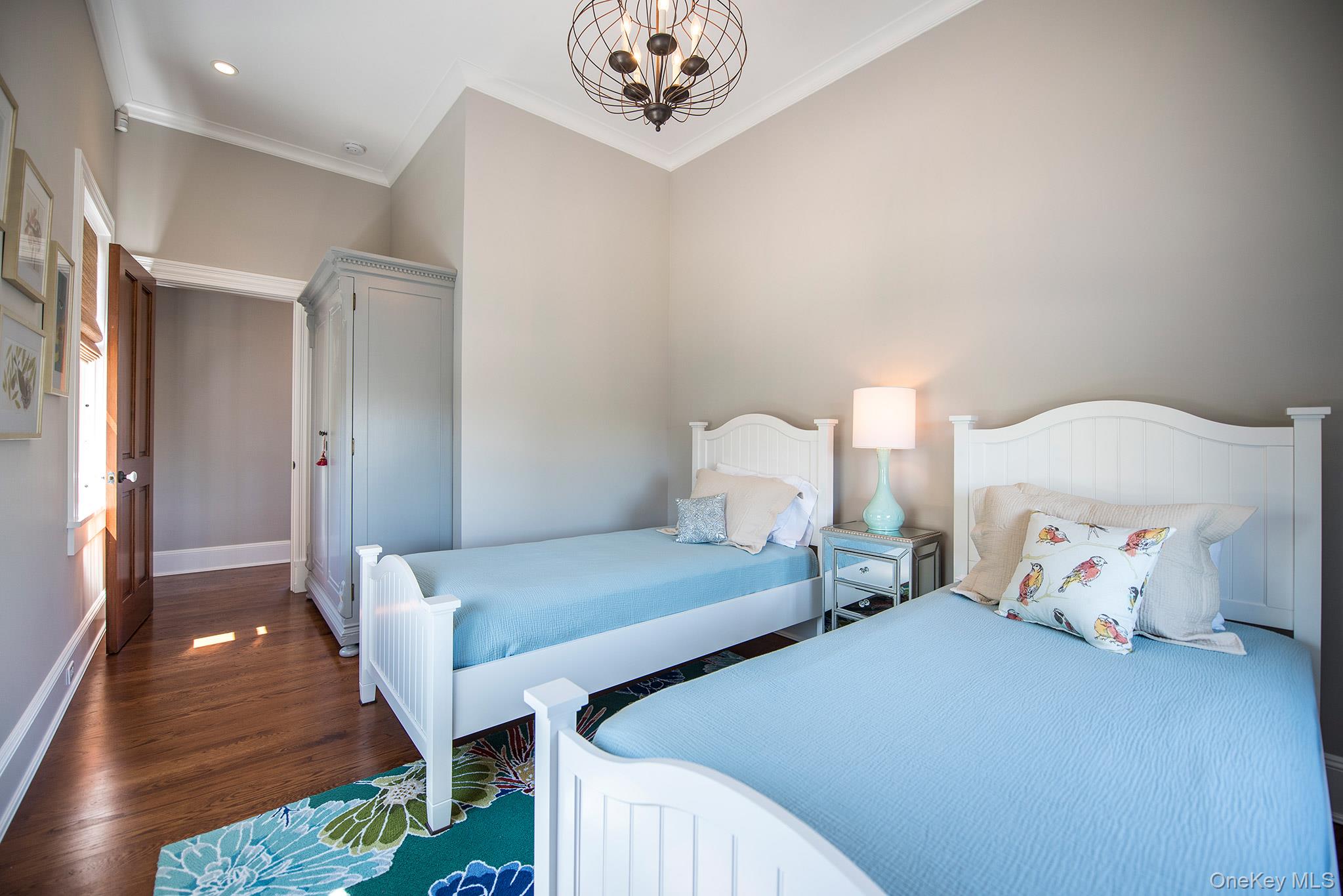 106 Old Depot Road Quogue, NY 11959 - Photo 23 of 34 a bedroom with two beds and a chandelier