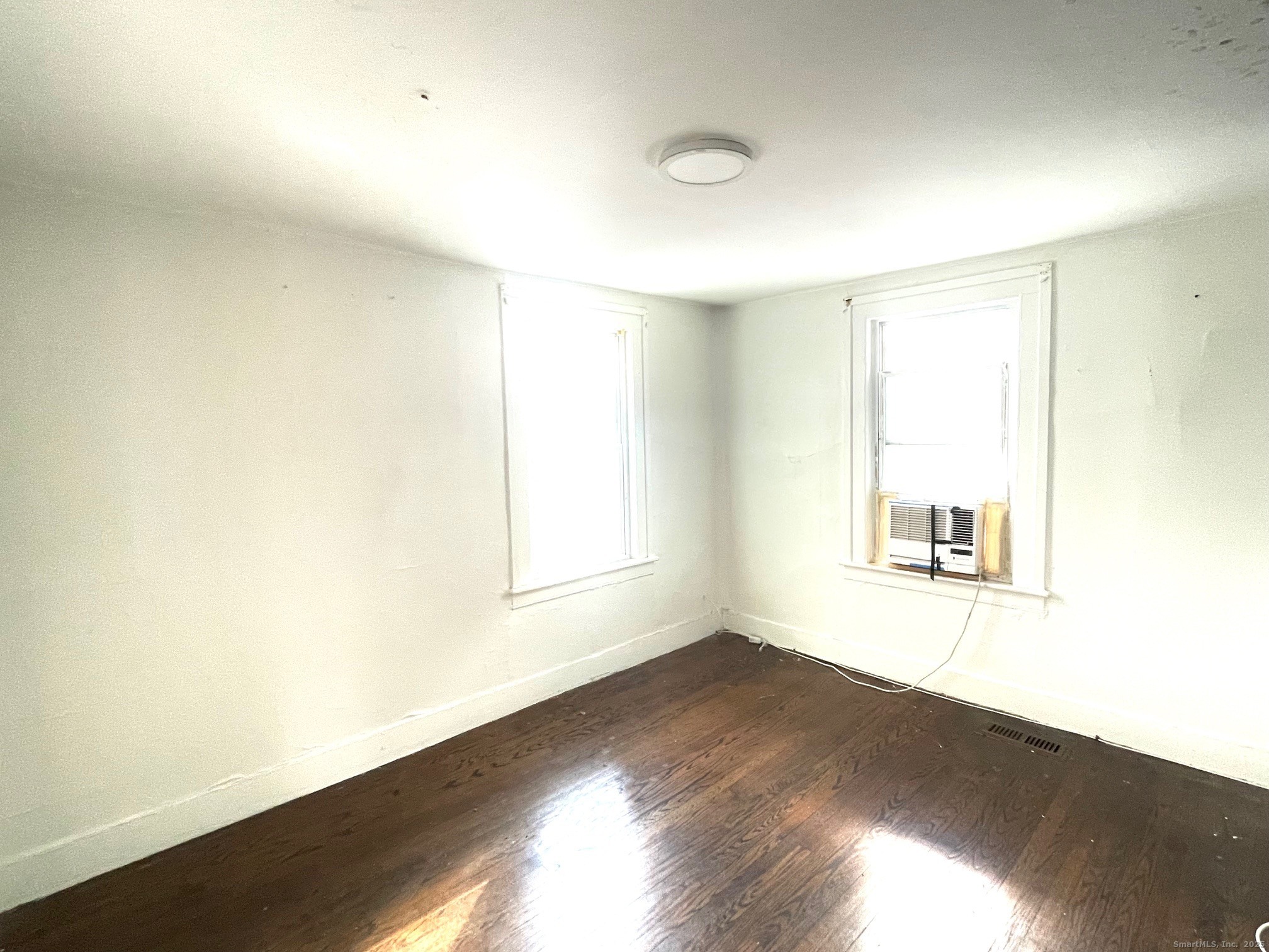184 Park Street Bridgeport, CT 06608 - Photo 5 of 7 an empty room with wooden floor and windows
