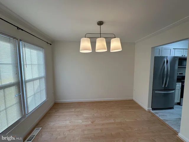 an empty room with chandelier fan and windows
