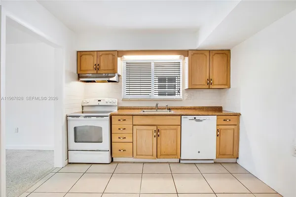 a kitchen with granite countertop white cabinets stainless steel appliances a sink and a window