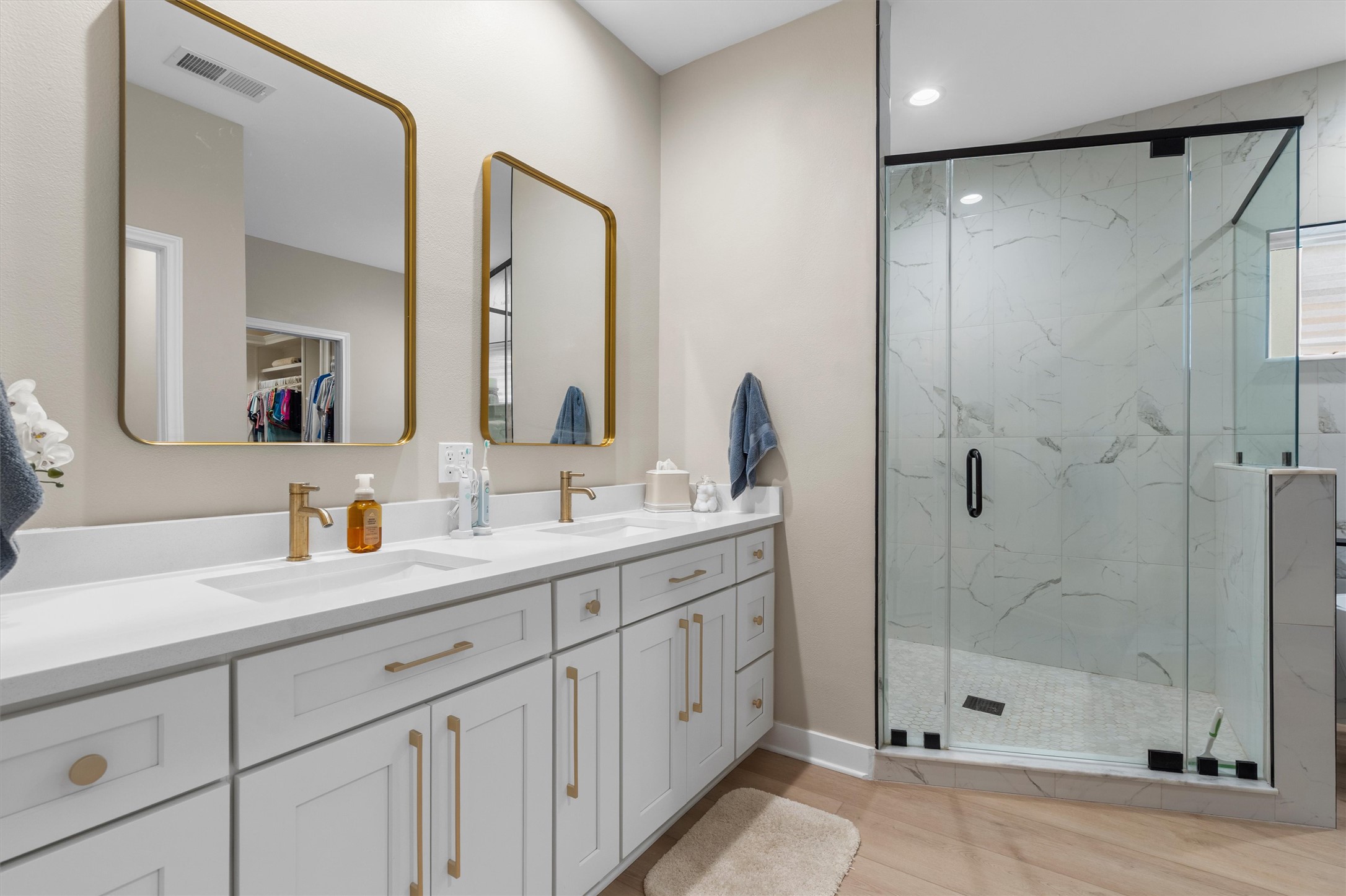 307 Hurst Creek Road Austin, TX 78734 - Photo 19 of 40 Dual vanity featuring white shaker cabinetry with gold-finish hardware, a white countertop, and rectangular undermount sinks