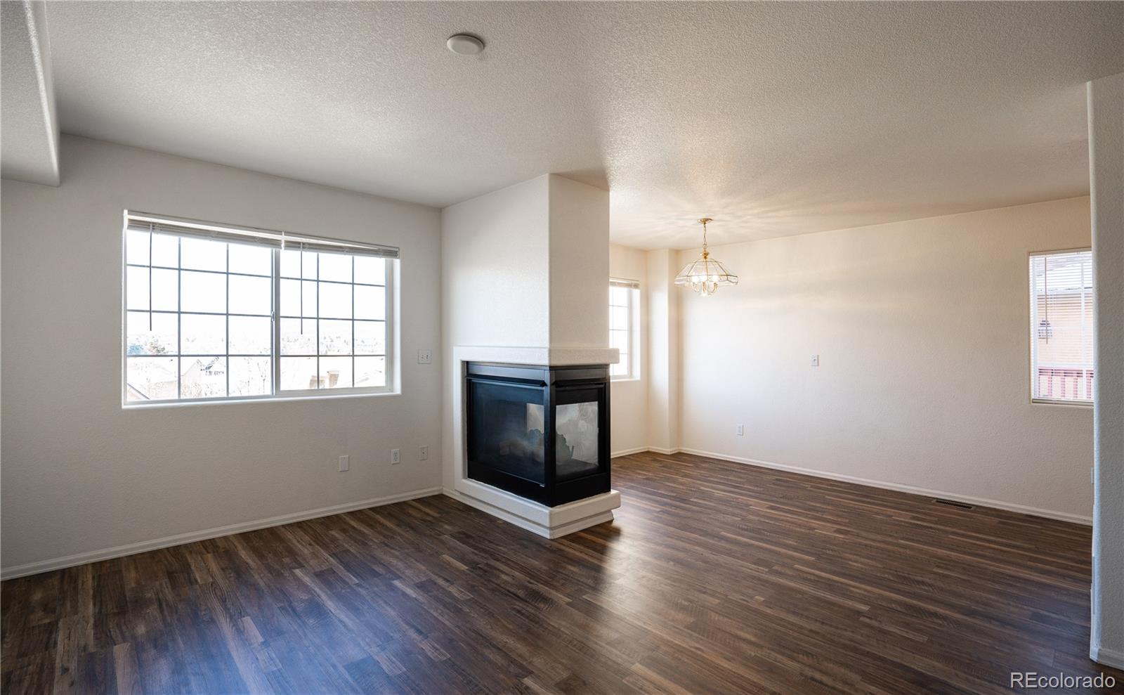 672 Bosque Vista Point, Unit 26 Colorado Springs, CO 80916 - Photo 7 of 25 an empty room with wooden floor and windows