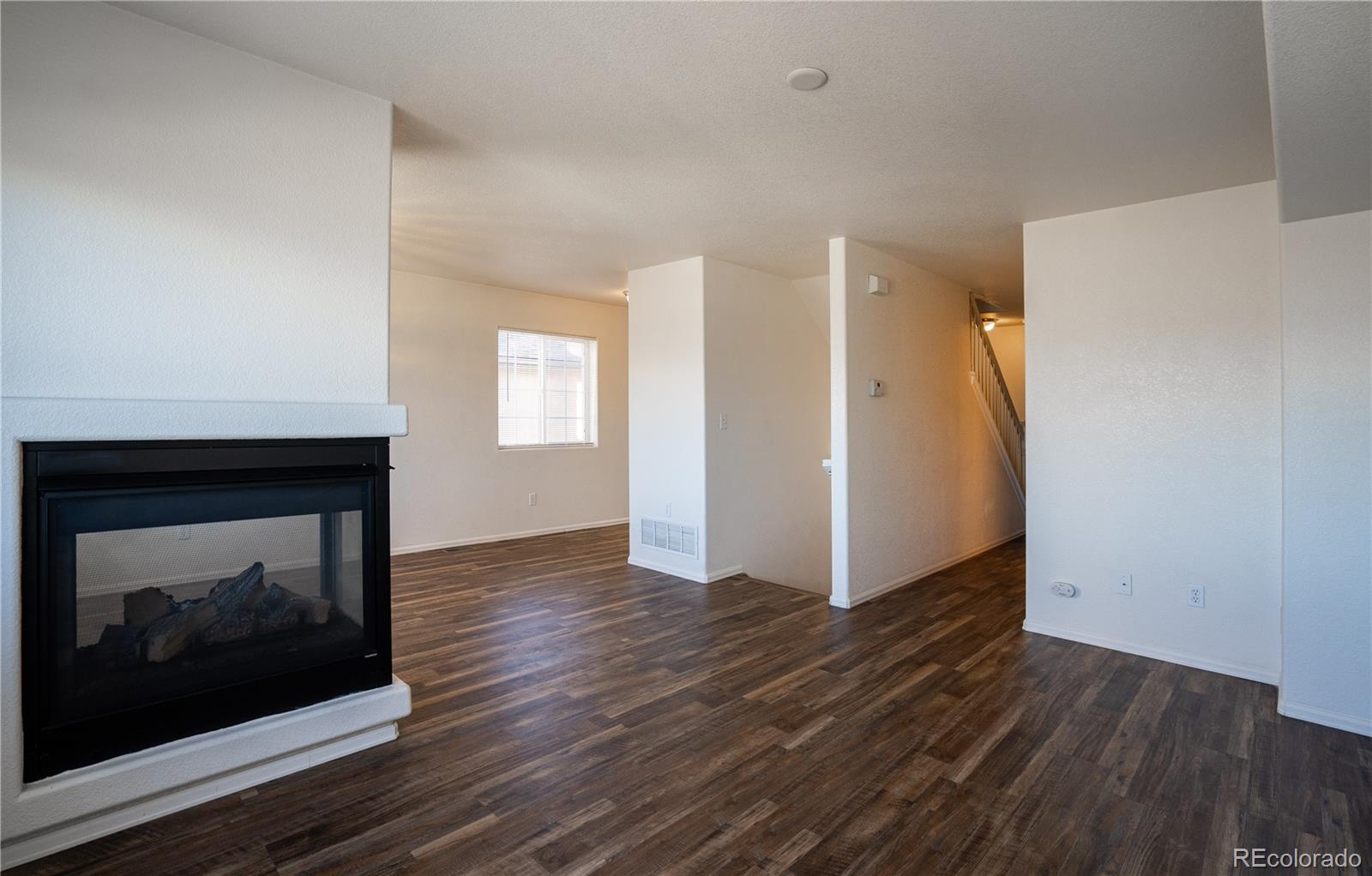 672 Bosque Vista Point, Unit 26 Colorado Springs, CO 80916 - Photo 8 of 25 a view of an empty room with wooden floor and a fireplace