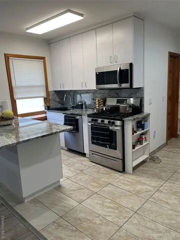 a kitchen with stainless steel appliances granite countertop a stove a refrigerator and a cabinets