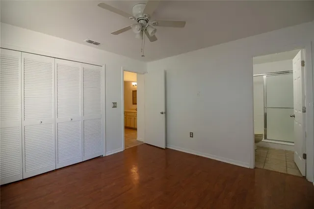 an empty room with closet and a ceiling fan