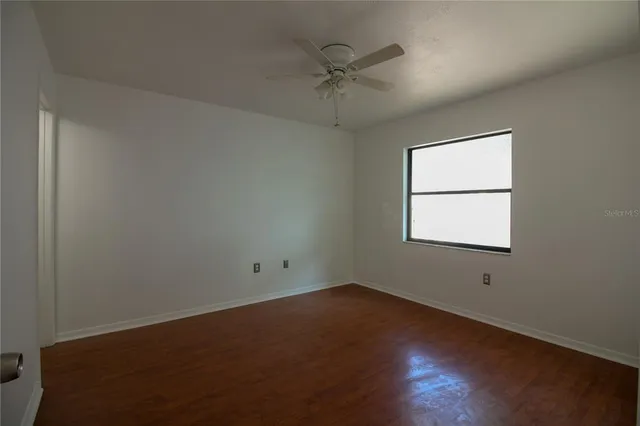an empty room with a window and a ceiling fan