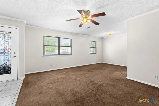 an empty room with windows and fan