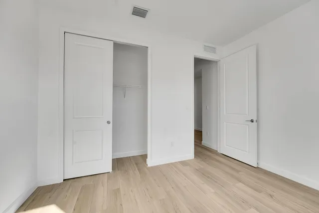 a view of an empty room with closet and wooden floor