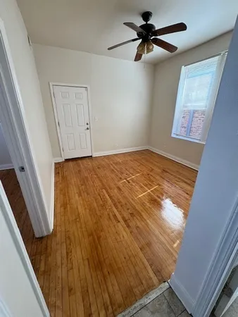 a view of a room with a ceiling fan and hardwood floor