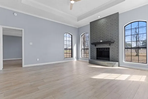 an empty room with windows and fireplace