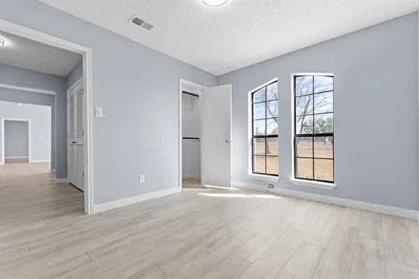 a view of an empty room with wooden floor and windows