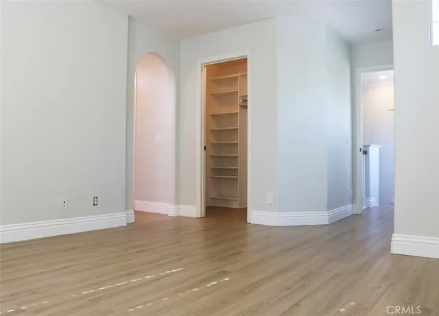 a view of an empty room with wooden floor and closet