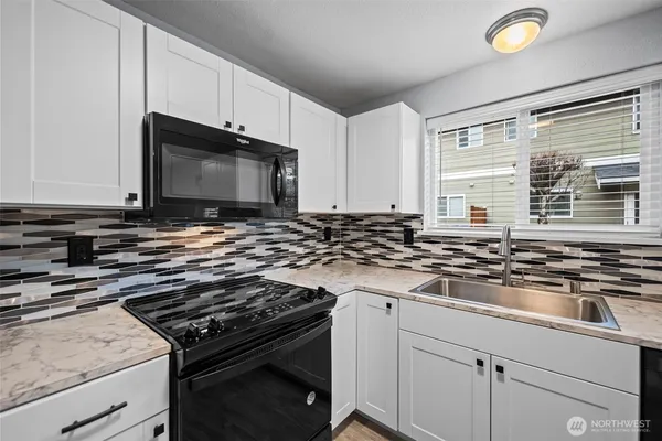 a kitchen with granite countertop a stove and a microwave