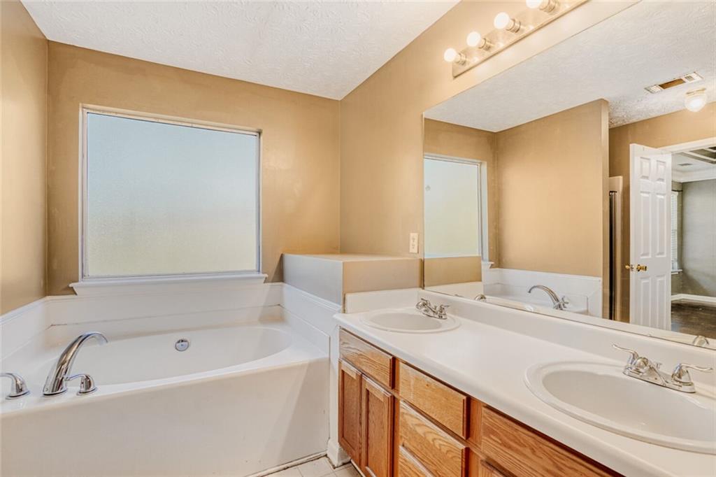 1298 Sierra Ridge Place Southeast Loganville, GA 30052 - Photo 18 of 29 a bathroom with a tub sink and mirror