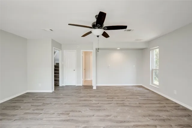 a view of empty room with wooden floor and ceiling fan