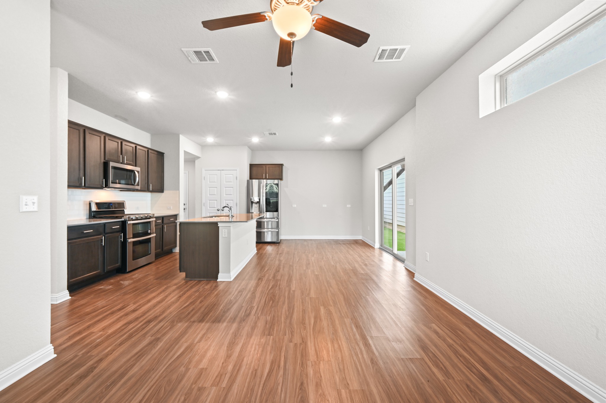 8201 Frida Bend Austin, TX 78744 - Photo 14 of 29 Open-concept living area with lustrous wood flooring and a modern kitchen.