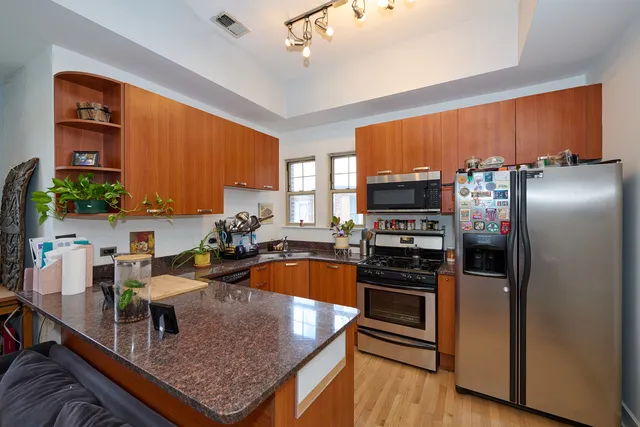 a kitchen with stainless steel appliances granite countertop a refrigerator a stove and a sink with wooden floor