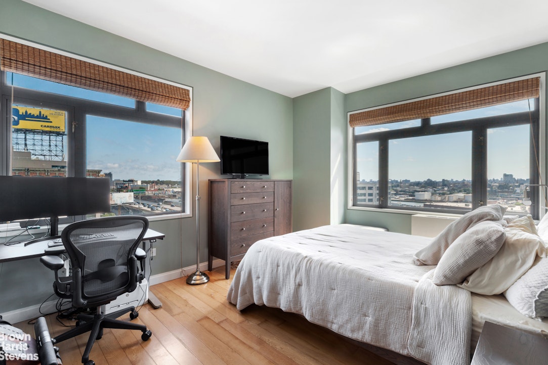 11-02 49th Avenue, Unit 8A Queens, NY 11101 - Photo 6 of 36 a bedroom with a bed and a flat tv screen next to a window