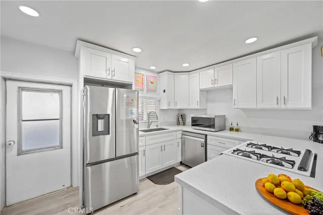 a kitchen with a refrigerator a stove a sink and white cabinets
