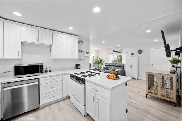 a kitchen with stainless steel appliances a stove a sink and white cabinets with wooden floor