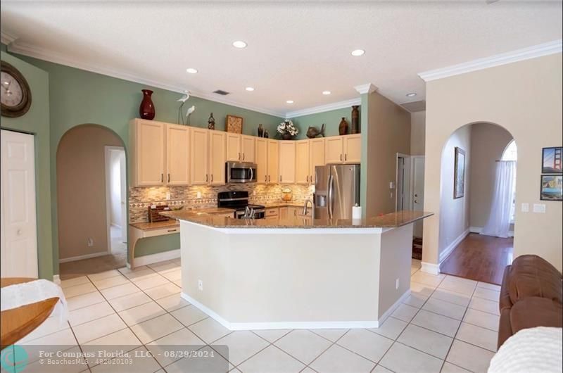 12253 Rockledge Circle Boca Raton, FL 33428 - Photo 10 of 22 a large kitchen with stainless steel appliances kitchen island granite countertop a refrigerator a stove a sink and a dining table with wooden floor