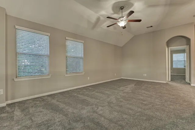 an empty room with a chandelier fan and windows
