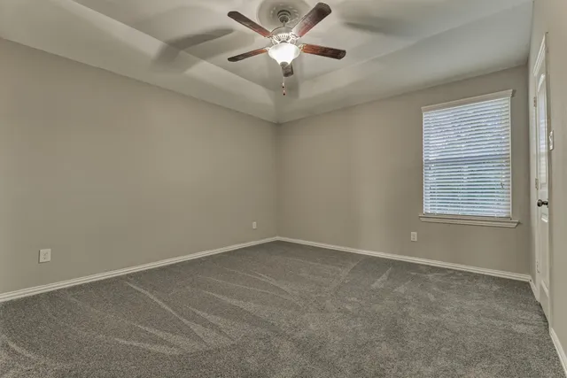 an empty room with windows and fan chandelier fan