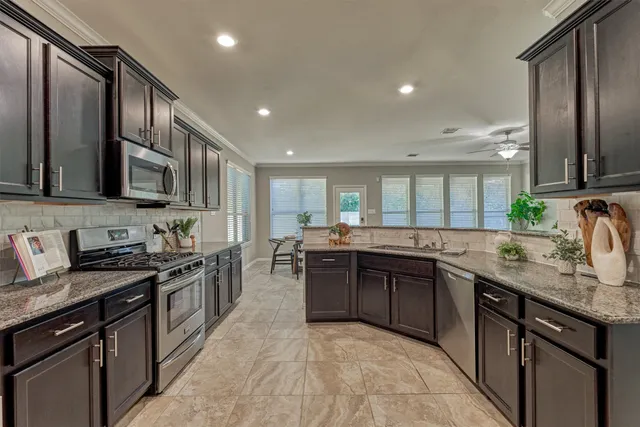 a kitchen with stainless steel appliances granite countertop sink stove top oven and granite counter top