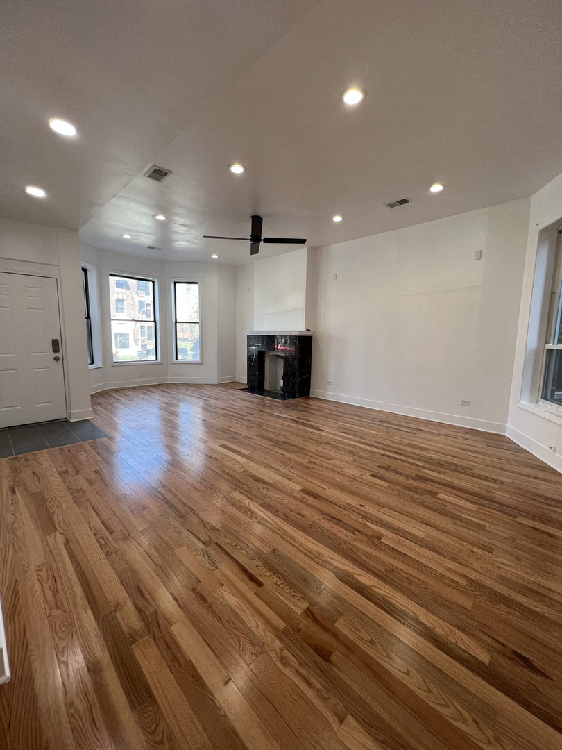 4813 South Prairie Avenue Chicago, IL 60615 - Photo 2 of 27 an empty room with wooden floor and fireplace