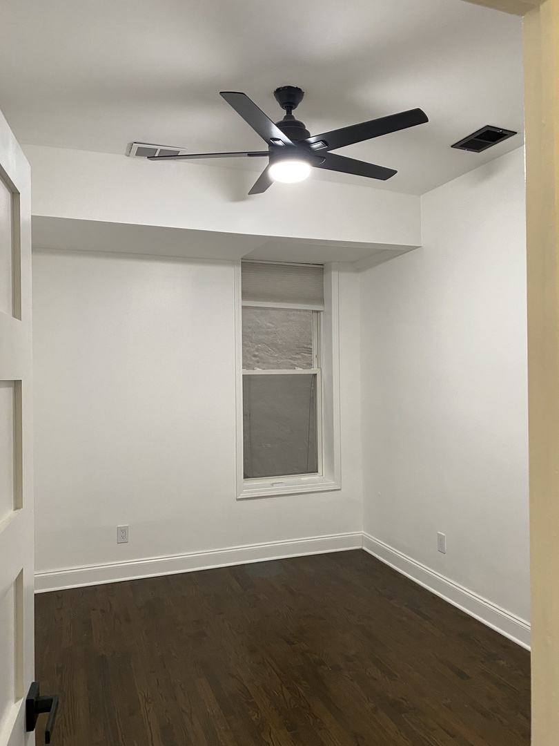 4813 South Prairie Avenue Chicago, IL 60615 - Photo 24 of 27 a view of an empty room with wooden floor and a window