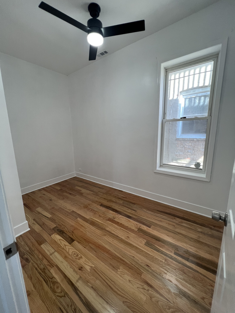 4813 South Prairie Avenue Chicago, IL 60615 - Photo 5 of 27 an empty room with wooden floor cabinet and windows