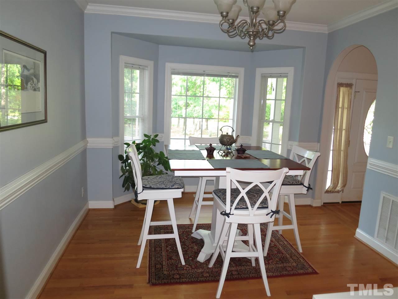 1328 Taylor Farm Road Raleigh, NC 27603 - Photo 4 of 24 a dining room with wooden floor a chandelier a wooden table and chairs