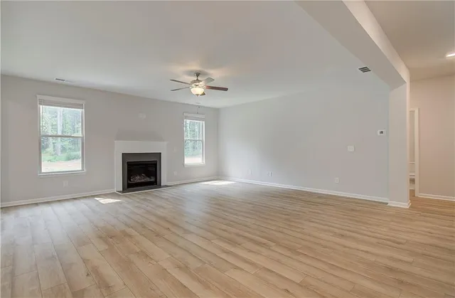 an empty room with windows fireplace and wooden floor