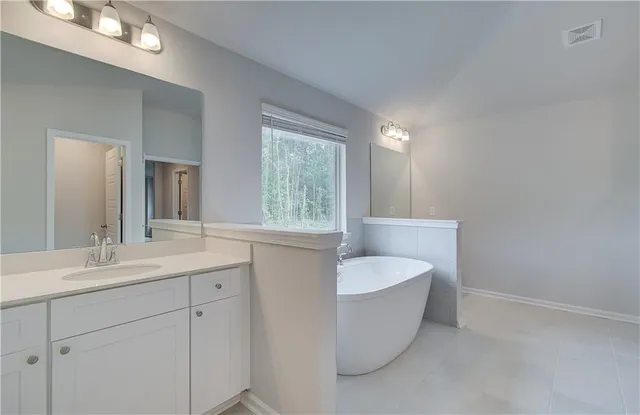 a spacious bathroom with a bathtub sink and mirror