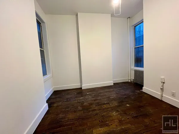 a view of an empty room with wooden floor and closet