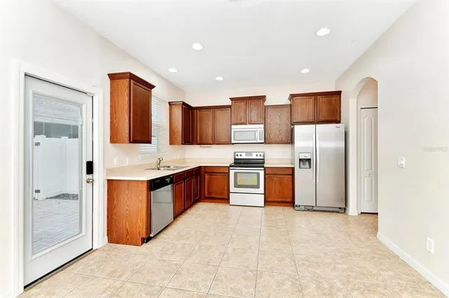 a large kitchen with stainless steel appliances kitchen island granite countertop a refrigerator and a sink