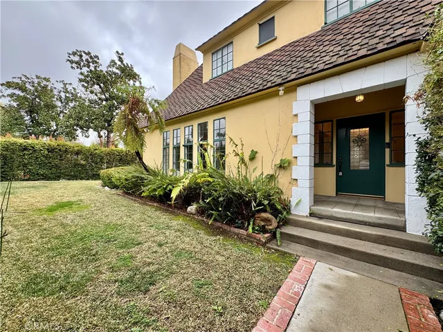 a view of a house with potted plants and a bench in front of it