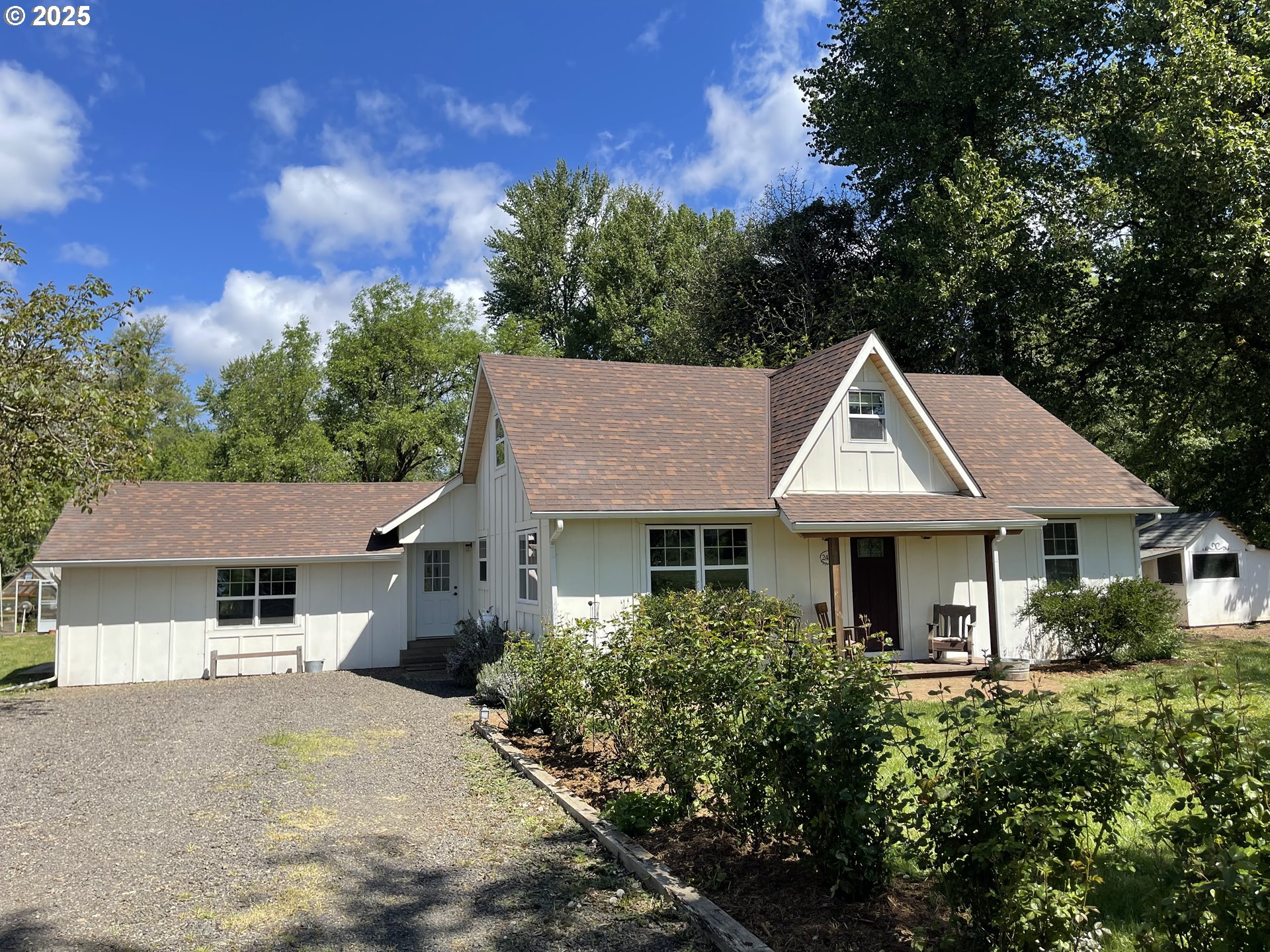 a view of a house with a yard plants and large tree
