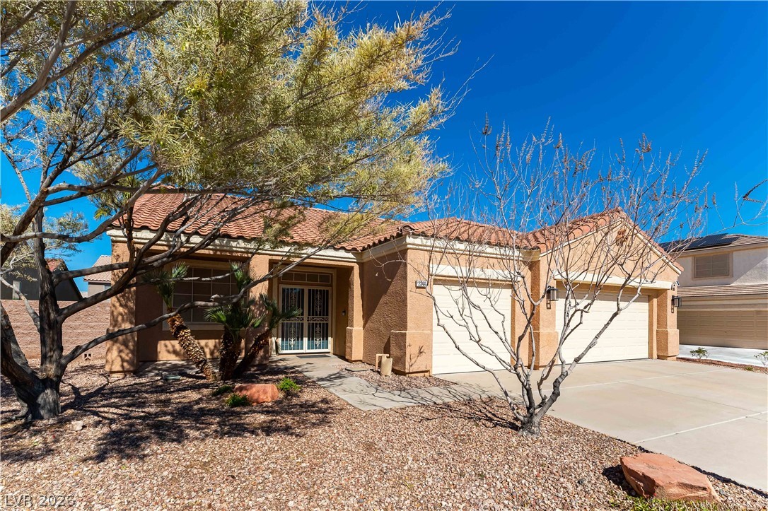 2344 Teton Ranch Avenue Henderson, NV 89052 - Photo 23 of 32 View of front facade with an attached garage, stucco siding, driveway, and a tiled roof