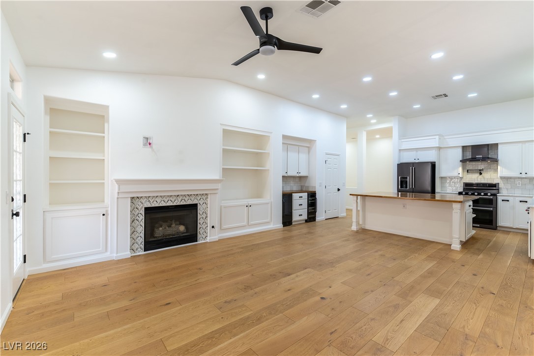 2344 Teton Ranch Avenue Henderson, NV 89052 - Photo 6 of 32 Unfurnished family room with a fireplace, vaulted ceiling, French Oak floors, built in bar and wine rack, ceiling fan, and recessed lighting