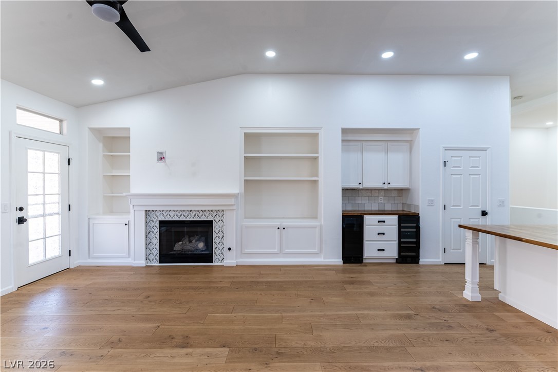 2344 Teton Ranch Avenue Henderson, NV 89052 - Photo 7 of 32 Unfurnished family room featuring vaulted ceiling, ceiling fan, a tile fireplace, light wood finished floors, and recessed lighting