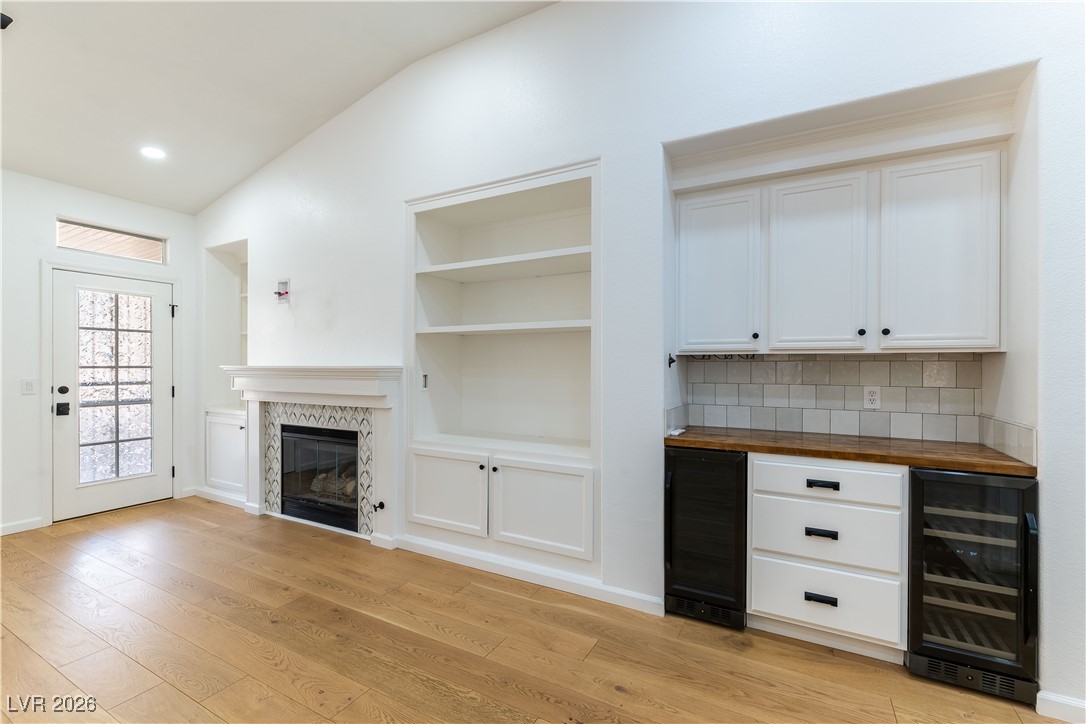 2344 Teton Ranch Avenue Henderson, NV 89052 - Photo 8 of 32 Unfurnished family room featuring vaulted ceiling, ceiling fan, a tile fireplace, light wood finished floors, and recessed lighting