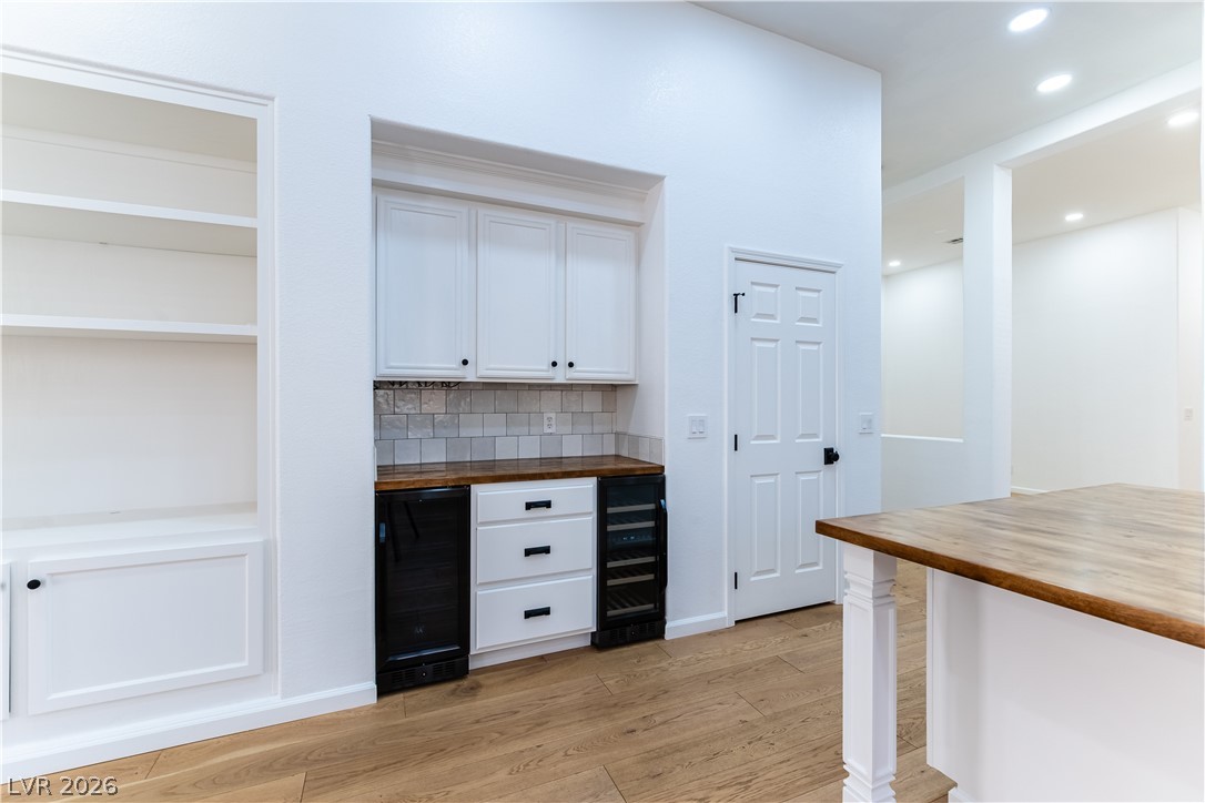 2344 Teton Ranch Avenue Henderson, NV 89052 - Photo 9 of 32 Indoor dry bar with butcher block counters, white cabinetry, decorative backsplash, light wood-type flooring, and wine cooler