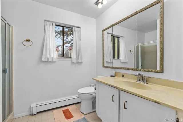 a bathroom with a toilet a sink a mirror and a window