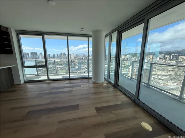 a view of an empty room with wooden floor and a window