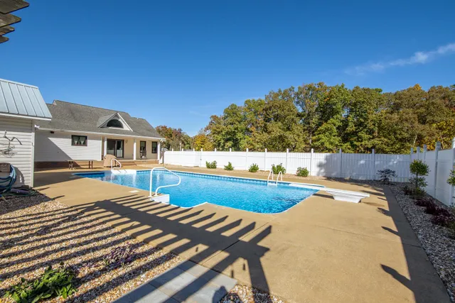 a view of a house with pool and wooden fence