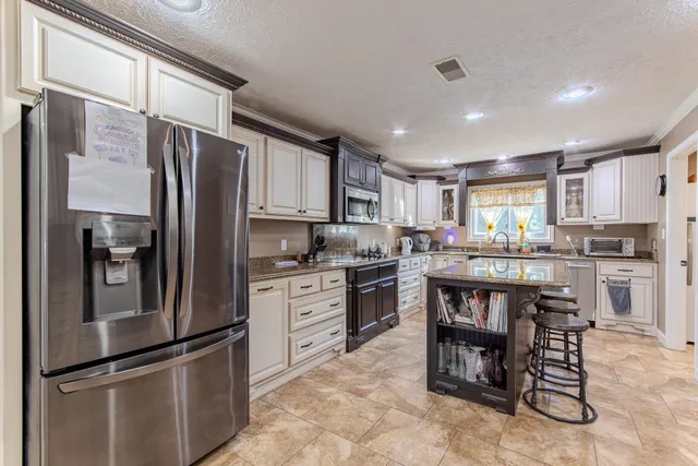 a kitchen with granite countertop stainless steel appliances a refrigerator and a stove top oven