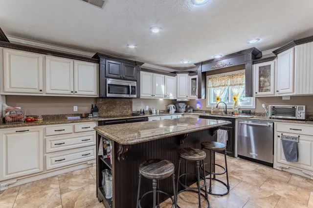 a kitchen with stainless steel appliances granite countertop a stove top oven a sink dishwasher and white cabinets with wooden floor